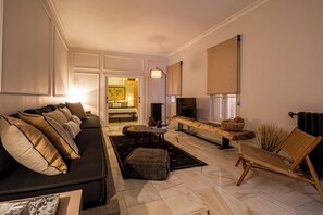Ein modernes Wohnzimmer mit einer Couch, einem Couchtisch, einem Fernseher und einem Sessel.