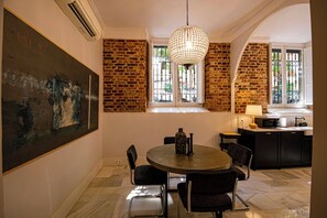 Un comedor con una mesa redonda, sillas, una lámpara colgante y una pared de ladrillo.