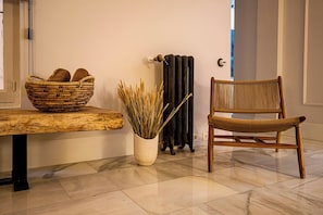 Ein Zimmer mit einem Holztisch, einem Korbstuhl, einem gewebten Korb und einer Vase mit Trockenpflanzen.