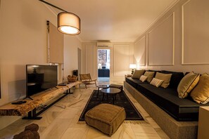 A modern living room with a flat-screen TV, a sofa, a coffee table, and a seating area with a bench. - 100 m² of luxury in the heart of the Salamanca neighborhood. (Madrid)