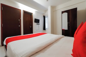 Habitació d'hotel amb un llit, dues portes, una televisió i una finestra amb persianes.