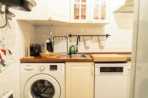 A compact kitchen with a washing machine, a dishwasher, a coffee maker, and a drying rack. - Cozy Apartment in Ventas (Madrid)