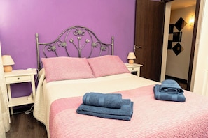 A bed with pink bedding, a metal headboard, and two side tables with lamps. - Cozy Apartment in Ventas (Madrid)