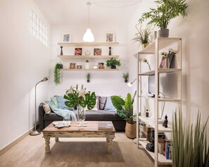 A cozy living room with a wooden coffee table, a grey sofa, and a bookshelf filled with books and plants. - Cosy and warm at Madrid's heart. A real finding. (Madrid)