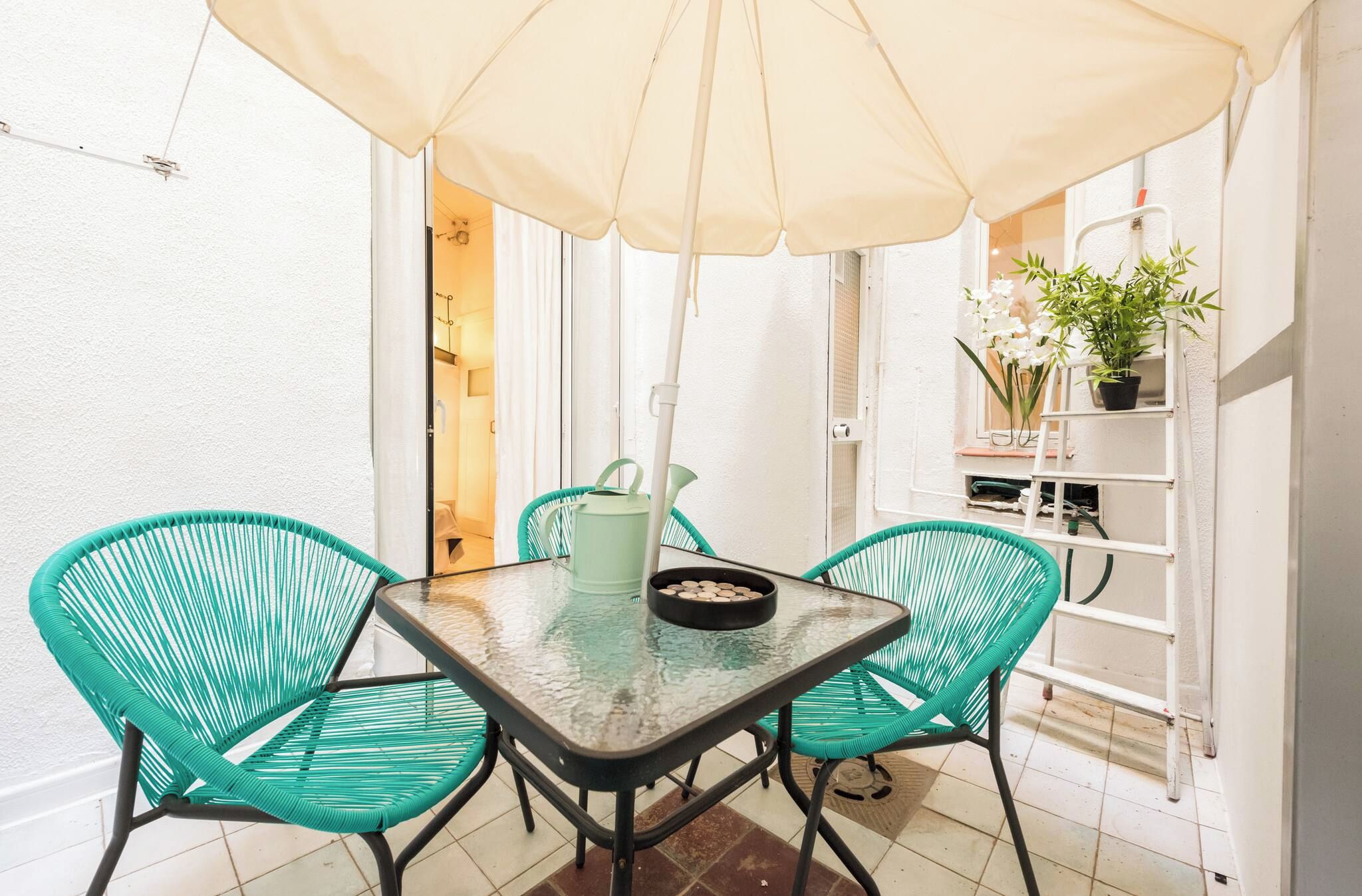 A small outdoor dining area with a table and chairs, a potted plant, and a white wall. - Cosy and warm at Madrid's heart. A real finding. (Madrid)