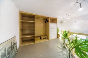 A room with a large open closet, a small table with a basket, and a potted plant. - Cosy and warm at Madrid's heart. A real finding. (Madrid)