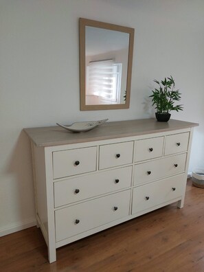 A white dresser with six drawers, a mirror above it, and a potted plant on top. - Urban Serenity Apartment (Madrid)