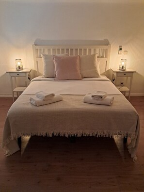 A neatly made bed with a headboard, two bedside tables with lamps, and towels on the bed. - Urban Serenity Apartment (Madrid)