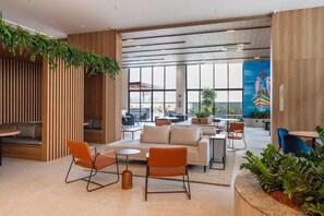 A modern lounge area with seating arrangements, a large window offering a view, and a mural on the wall.