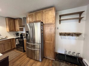 Une cuisine avec des meubles de rangement en bois, un réfrigérateur en acier inoxydable, une cuisinière et un four encastré.