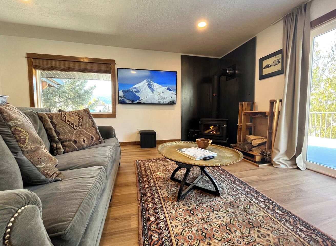 A living room with a sofa, a coffee table, a fireplace, and a large window.