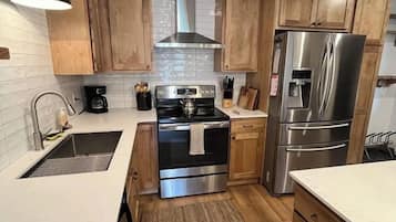 A modern kitchen with wooden cabinets, stainless steel appliances, and a white countertop.