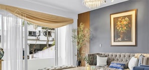 En stue med en grå sofa, et indrammet blomsterkunstværk og en potteplante.