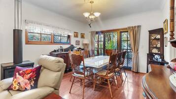 Un espace repas comprenant une grande table, des chaises et une vue sur l’extérieur, visible à travers une porte vitrée.