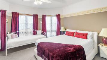 Une chambre d’hôtel avec deux lits, un ventilateur de plafond et une fenêtre avec des rideaux.