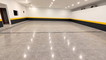 A spacious indoor area with a tiled floor and a yellow and black stripe running along the lower wall.