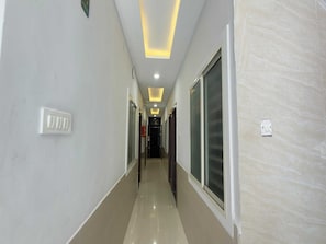 A hallway with a light switch, recessed ceiling lights, and a door at the end. - Deluxe Hotel C&D Stay (Indore)