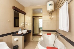 A bathroom with a bathtub, a sink, a mirror, and a towel rack. - Kadiga Villas - 3 Bedroom Villa (Bali)