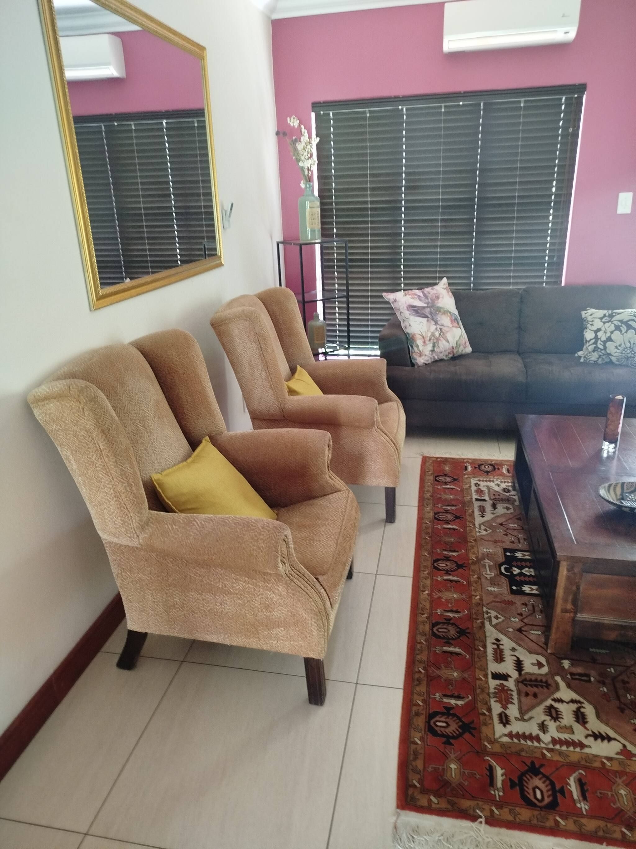 Una sala de estar con dos sillones, un sofá, una mesa de centro y una alfombra estampada.