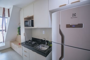 Eine moderne Küche mit weißen Schränken, einer schwarzen Arbeitsplatte und einem Kühlschrank von Electrolux.