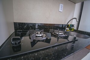A kitchen with a gas stove, a sink, and a countertop. - Bella V. Ap. 304 C - Andres Sardi (Ipojuca)