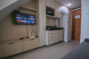 Eine moderne Küche mit Flachbildfernseher an der Wand, eingebauter Mikrowelle und Kühlschrank.