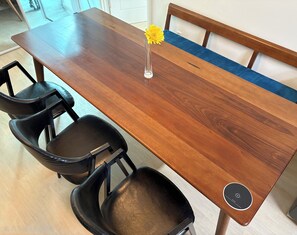 Een houten eettafel met een vaas vol gele bloemen, aangevuld met vier zwarte stoelen.