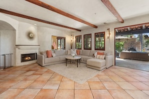 A spacious living room with a fireplace, a sectional sofa, and a patio area with outdoor seating. - Mediterranean style retreat. (Solana Beach)