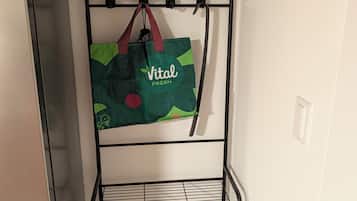 A metal rack with hooks, a green bag hanging, and a tiled floor.