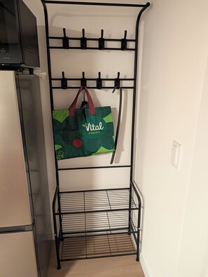 A metal rack with hooks, a green bag hanging, and a tiled floor.