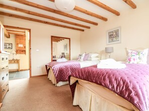 A bedroom with two beds, wooden beams on the ceiling, a dresser, and a mirror. - Ash Cottage (Truro)