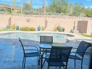 A pool with a table and chairs, surrounded by a brick wall and desert vegetation. - 
Luxurious Desert Oasis in gated Dove Mountain community with pool and hot tub (Marana)