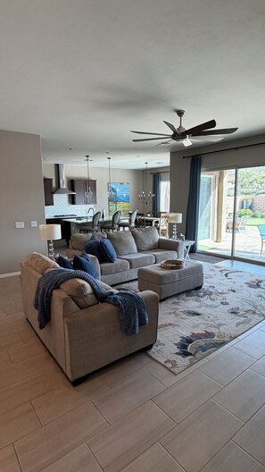 A modern living room with a sofa, ottoman, and a dining area in the background. - 
Luxurious Desert Oasis in gated Dove Mountain community with pool and hot tub (Marana)
