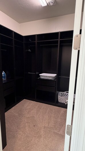 A closet with multiple shelves and a hanging rod, a small ironing board, and a laundry basket. - 
Luxurious Desert Oasis in gated Dove Mountain community with pool and hot tub (Marana)