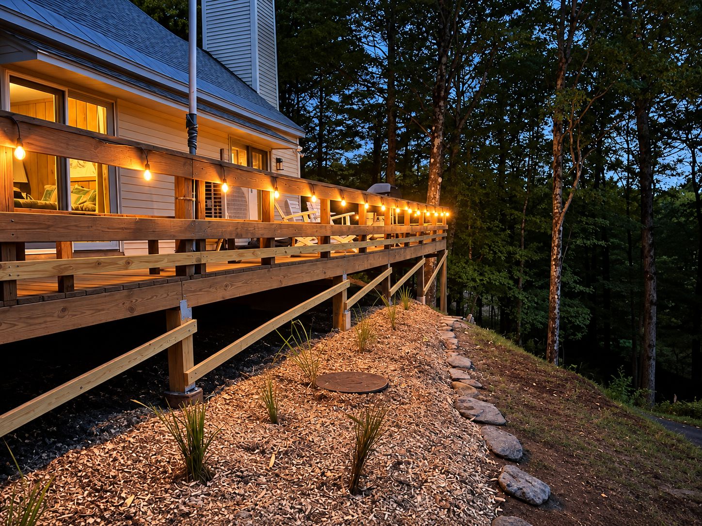 A wooden deck with string lights, a stone pathway, and a house with windows.