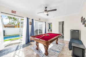 A pool room with a pool table, ceiling fan, and exit sign. - The Beachside Escape I New Pool & Spa! (Hollywood)