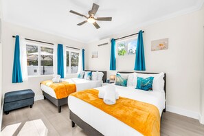 A hotel room with two beds, a ceiling fan, and a view of the outdoors. - The Beachside Escape I New Pool & Spa! (Hollywood)