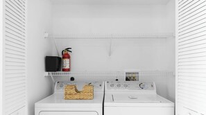 A laundry room with two white washing machines, a fire extinguisher, and a shelf above the machines. - 1 BR APT Resort Style - Resort Amenities (Hallandale Beach)