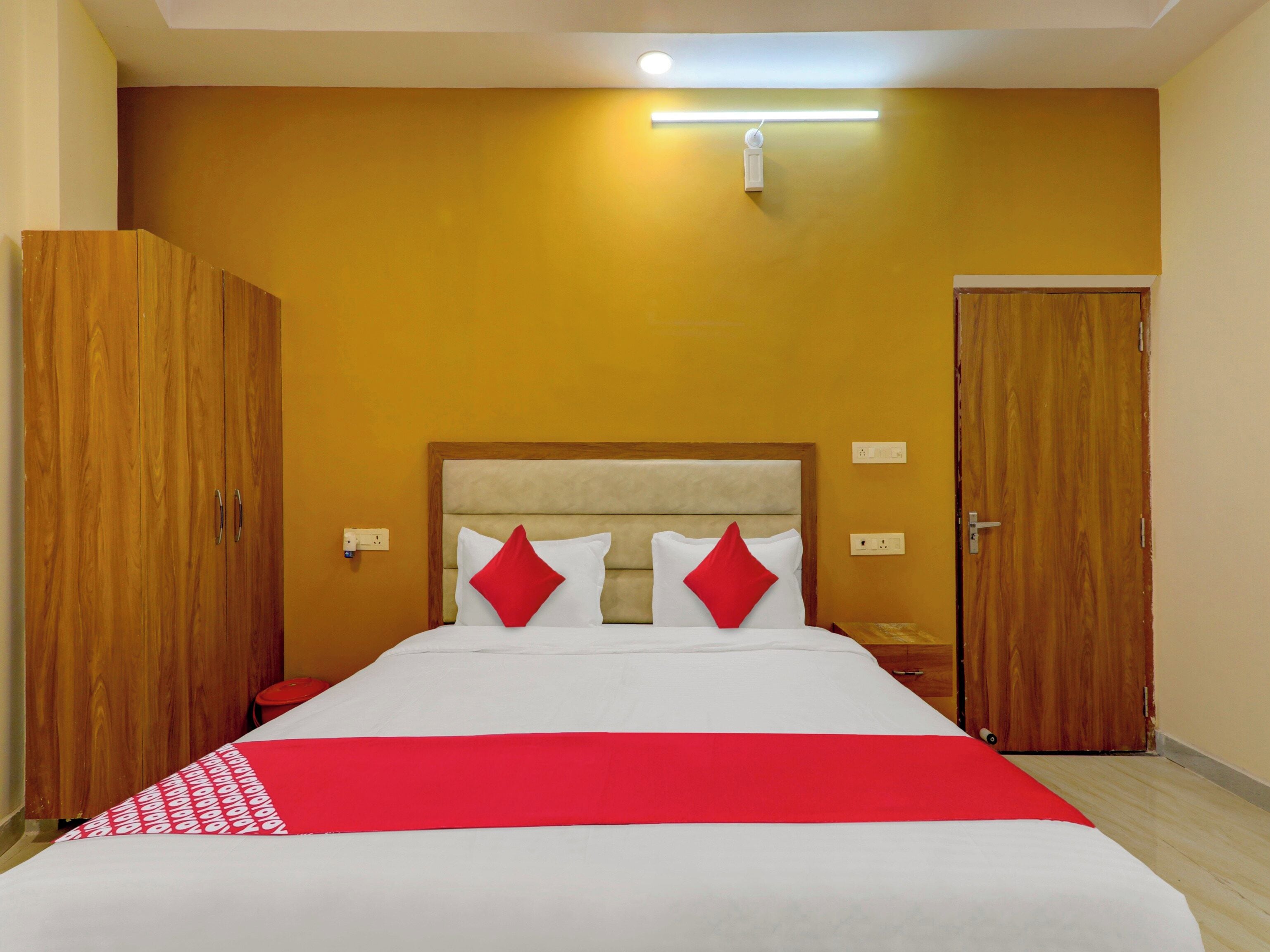 A hotel room with a bed, wooden wardrobe, and a door.