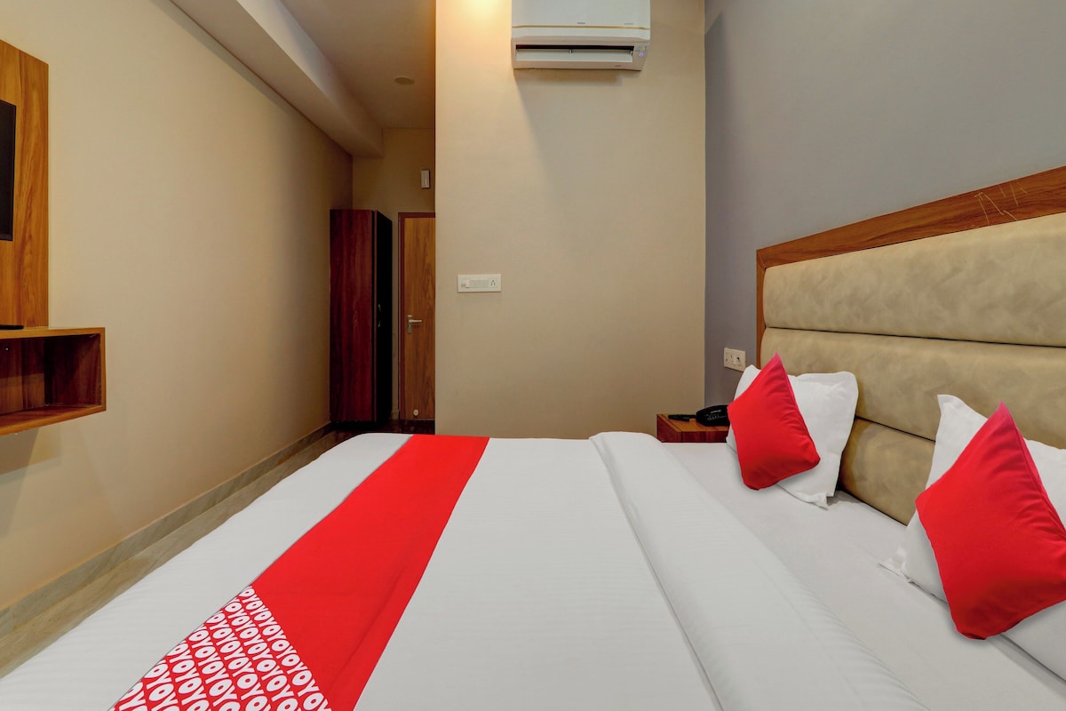 Ein Hotelzimmer mit Bett, Kissen, Nachttisch, Klimaanlage und einem Holzschrank.