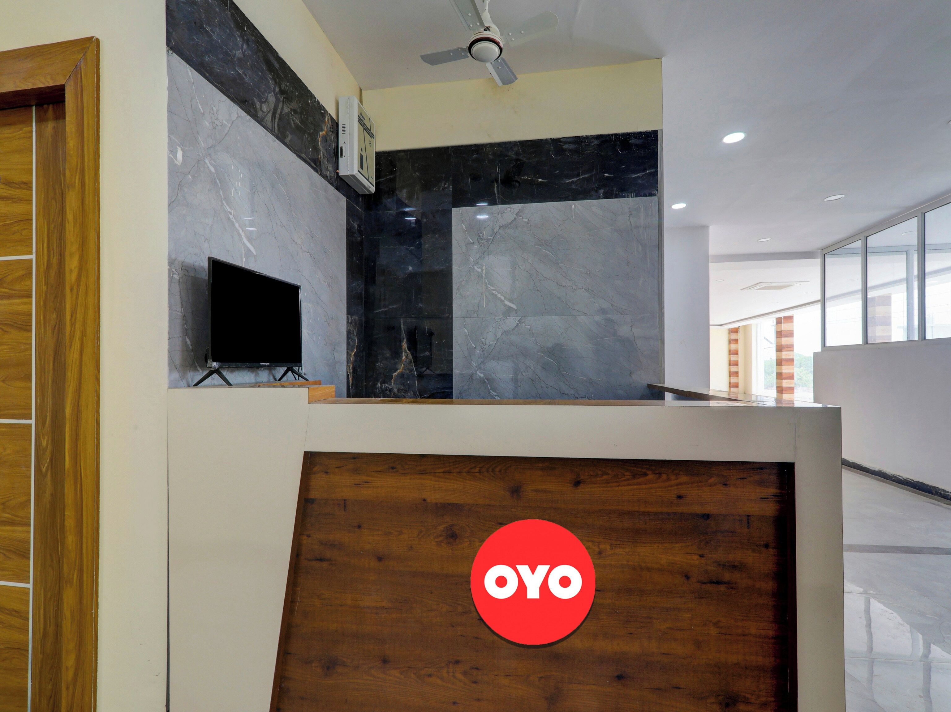 A reception area with a wooden reception desk, a television, and a logo on the wall.