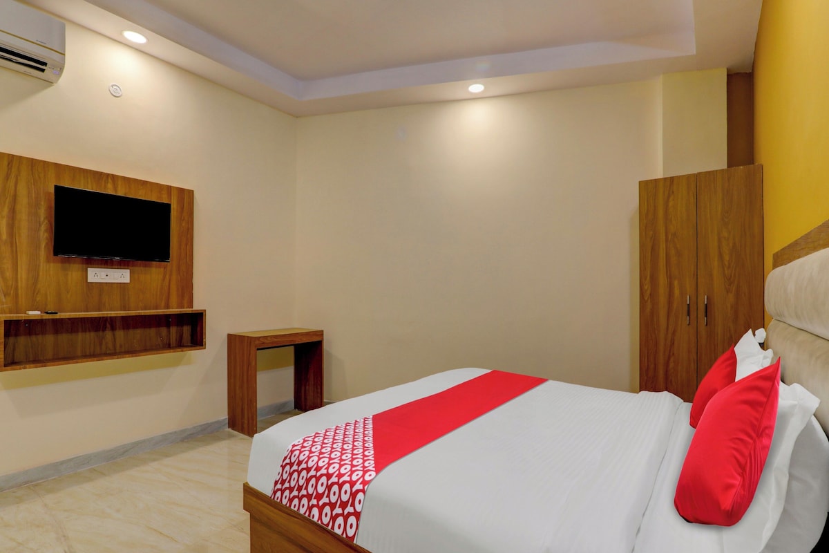 Una habitación de hotel con cama, televisión montada en la pared, armario y una mesita.