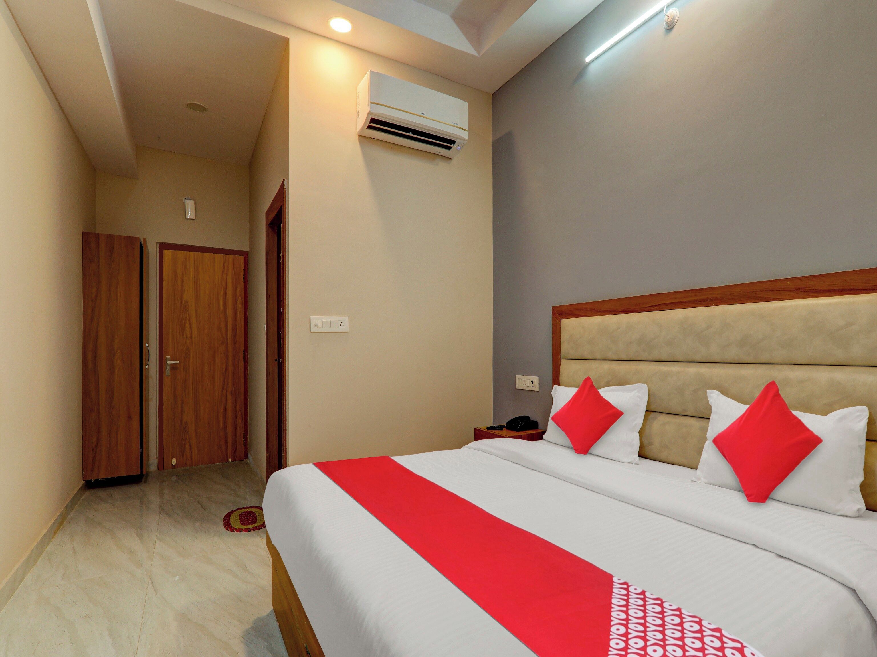 Una habitación de hotel con una cama, un armario, un aire acondicionado y una mesita de noche.