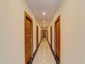 Un largo pasillo estrecho con puertas de madera a ambos lados y un piso de mármol pulido.