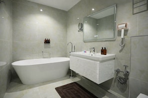 A modern bathroom with a freestanding bathtub, a vanity with a mirror, and a shower area. - Ramada by Wyndham (Nukus)