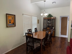 A dining room with a marble table, wooden chairs, a chandelier, and a cabinet with glass doors. - Panther Creek Retreat - Heart of The Woodlands (Spring)