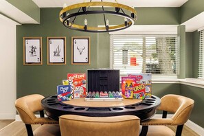 Uma área de refeições com mesa redonda, cadeiras e vários jogos de tabuleiro.