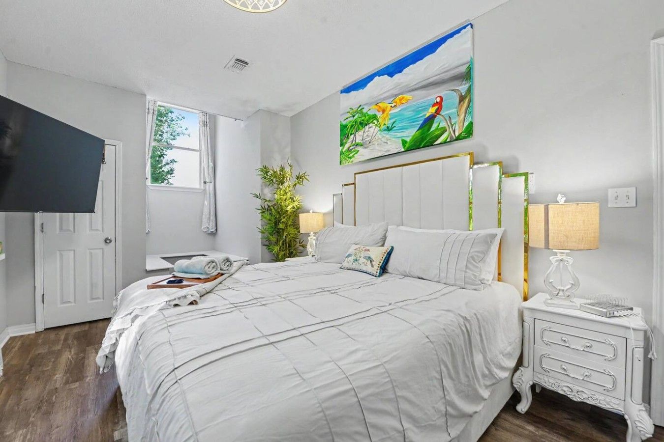 Une chambre à coucher avec un lit, des tables de chevet, une télévision et un tableau au mur.