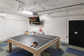 A ping pong table with a TV mounted on the wall and a door in the background. - Cottage by The Sea, Family Retreat w/ Game Room (Biloxi)