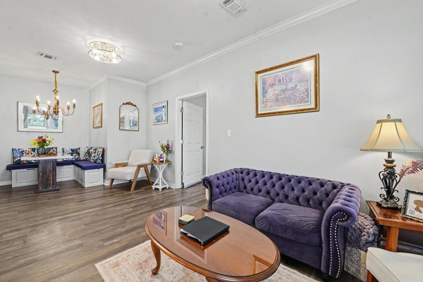 Un salon avec un canapé violet, une table basse en bois et une porte blanche.